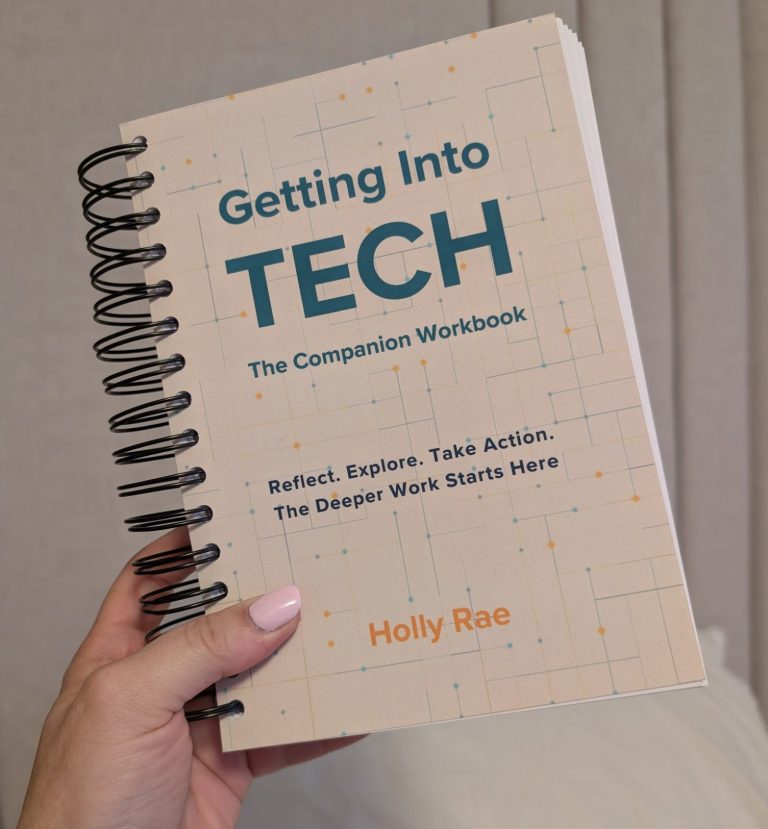 A left hand, holding the light coloured spiral bound book of getting into tech - the companion workbook
